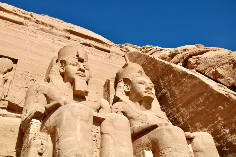 statues of pharaohs and queens in front of a rock formation